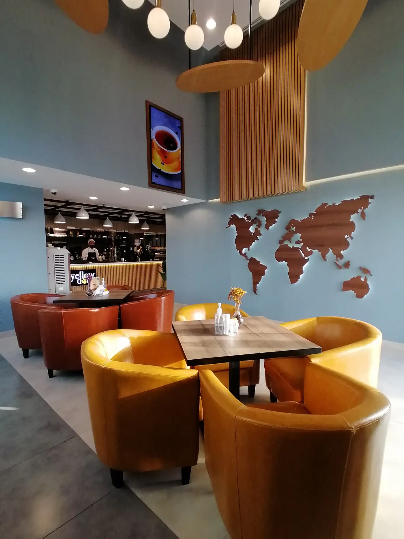 Inside Yellow Dot Cafe: yellow tub chairs under a world map wall